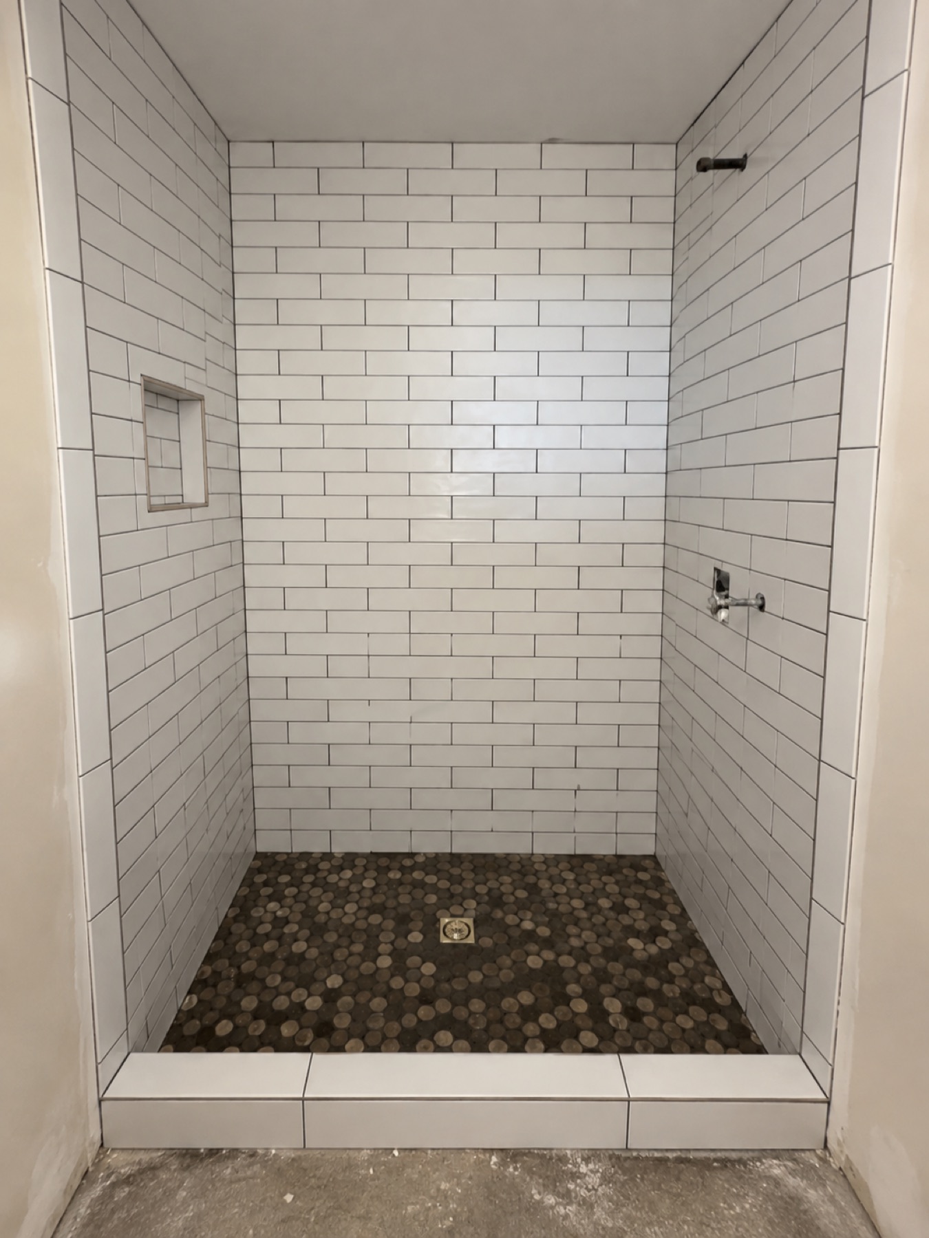 White subway tile shower with penny round tile floor